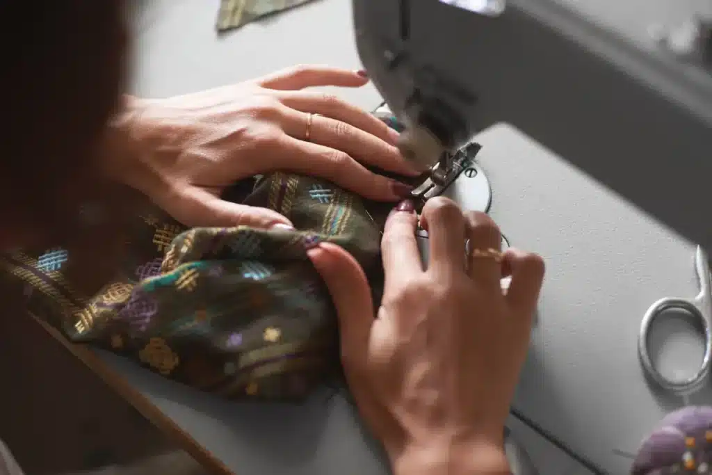 Couturi&egrave;re travaillant sur une machine &agrave; coudre &eacute;lectrique moderne fabriquant des v&ecirc;tements exclusifs dans un studio de mode.